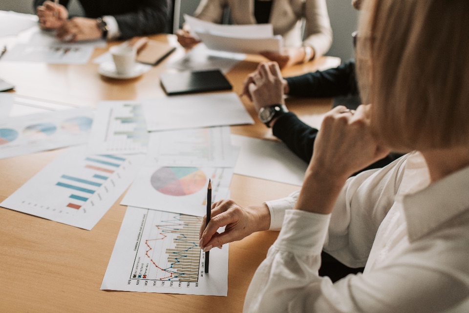 Close up of a business meeting with cost and performance charts spread across the table