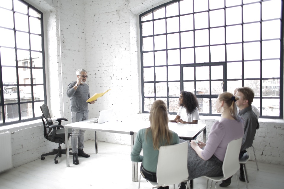 Team meeting in a bright open office as a director presents to employees