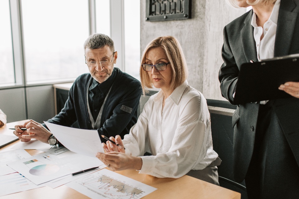Business professionals reviewing policy documents and reports around a meeting table