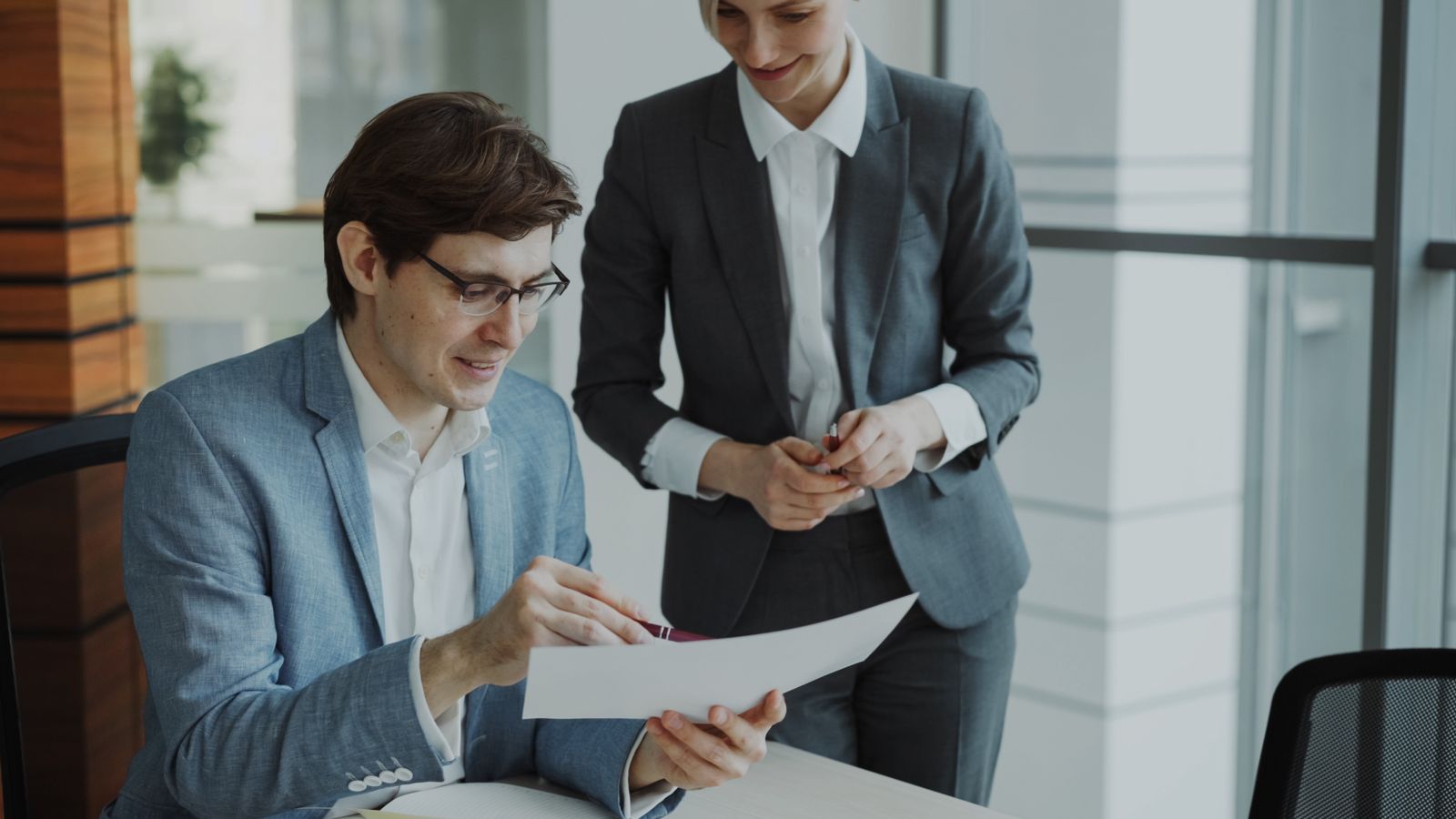 Two company directors reviewing documents together in a modern office