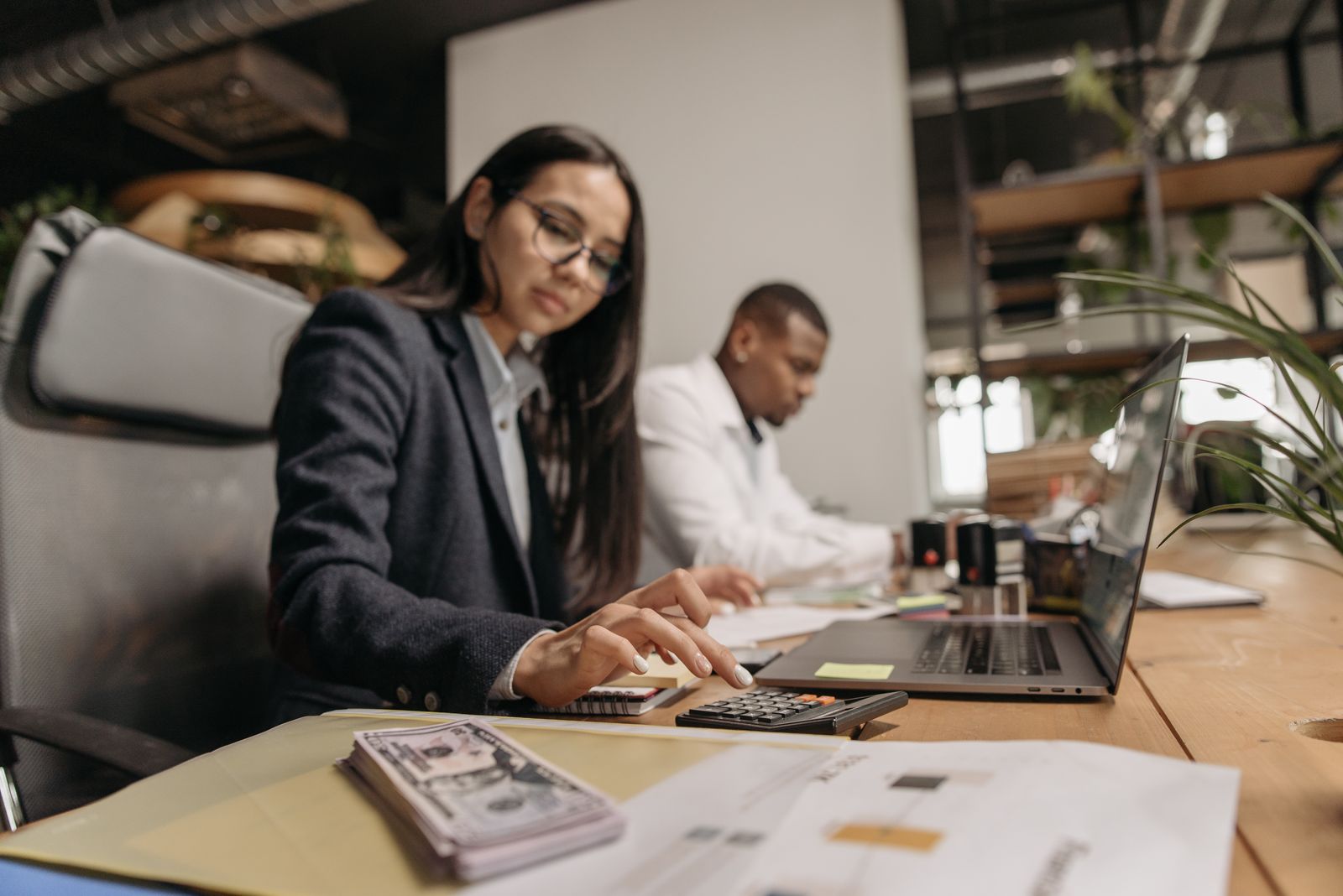 Two professionals reviewing company finances together with a calculator and paperwork