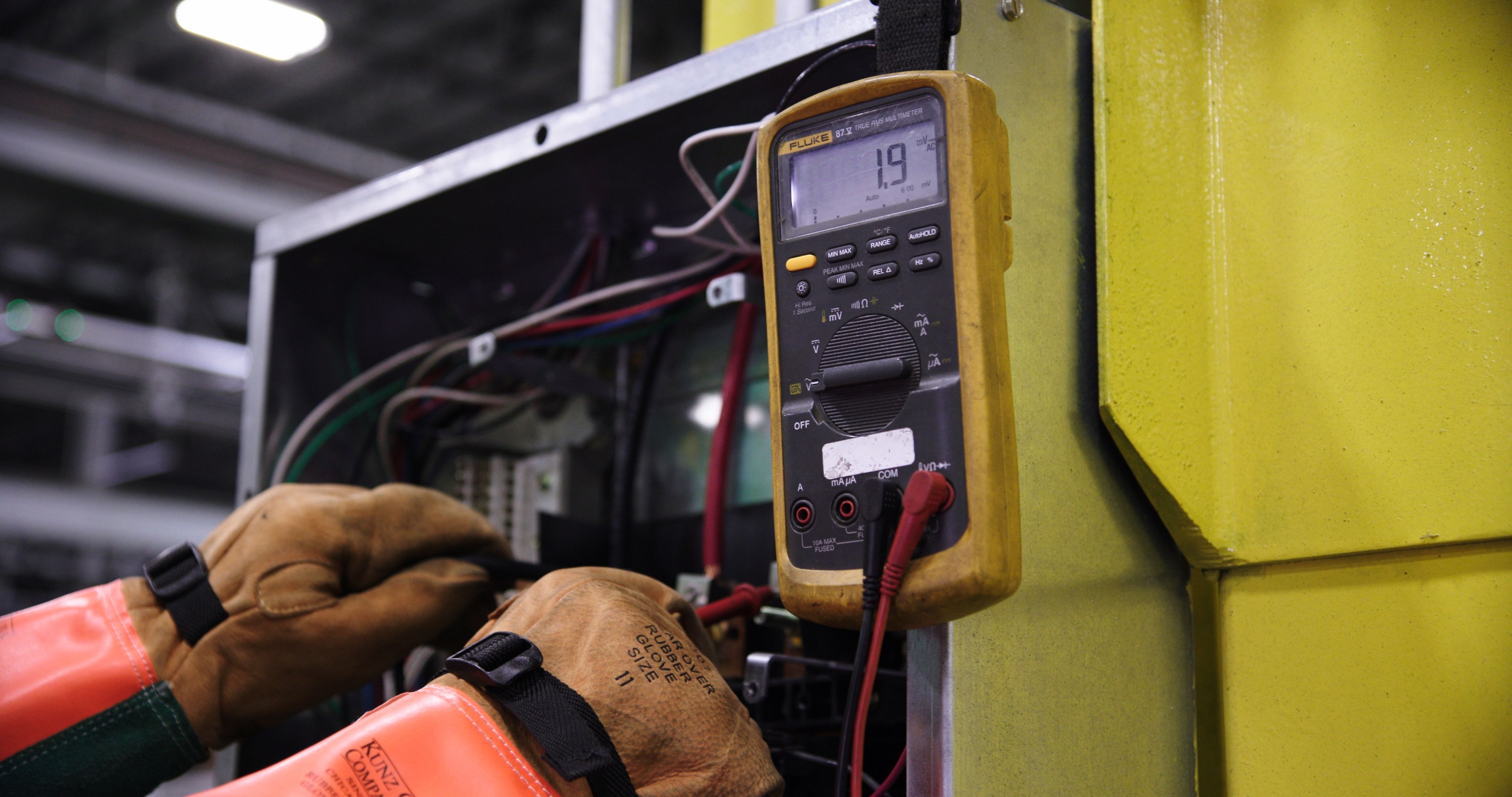 Self-employed electrician testing a circuit board with a multimeter, relying on healthy hands and mobility